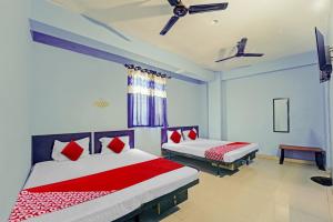 a bedroom with two beds with red and white pillows at Super OYO Flagship Glad Guest House in Patna