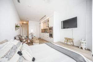 a white bedroom with a large bed and a living room at Downtown Toronto Gem in Toronto