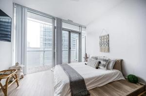 a white bedroom with a bed and a large window at Downtown Toronto Gem in Toronto