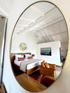 Andriana Resort & Spa في نوسي بي: مرآة تعكس غرفة نوم مع سرير وأريكة