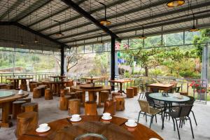 un restaurante con mesas y sillas de madera y ventanas en Nantou Xitou Riverside Homestay B&B en Lugu