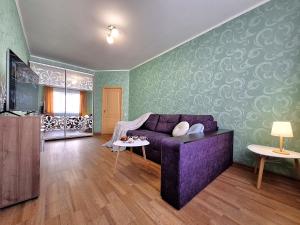 a living room with a purple couch and green walls at ЕКО-квартира на Садововому. Мережа Alex Apartments. Цілодобове безконтактне заселення in Shcherbani