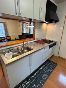 a kitchen with white cabinets and a sink and a kitchen rug at Independent House 沖縄VILLA YASUMIBA Okinawa Uruma in Uruma