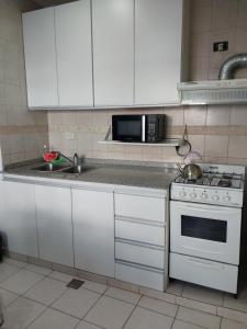 a kitchen with white cabinets and a stove and a microwave at Patagonia Relax- Depto zona céntrica y de servicios de salud in Comodoro Rivadavia