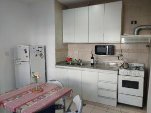 a kitchen with white cabinets and a table and a refrigerator at Patagonia Relax in Comodoro Rivadavia