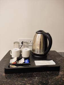a tea kettle and cups on a tray on a counter at Hotel Satsang Grand in Varanasi