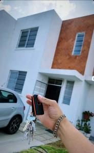 una persona che tiene un cellulare di fronte a una casa di Rinconada Cabrera ad Atlixco