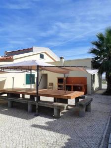 una mesa de picnic con una sombrilla delante de una casa en 10 bedrooms villa with private pool enclosed garden and wifi at Palmela en Palmela