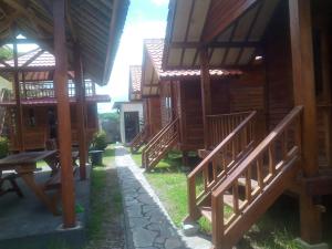 a row of wooden buildings with a table and benches at Mayeka Transit Hostel Bandara Internasional Lombok in Praya