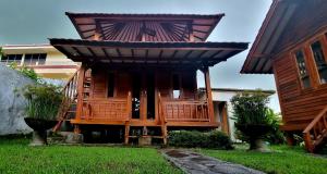 Mayeka Transit Hostel Bandara Internasional Lombok في برايا: منزل خشبي بسقف مقامر