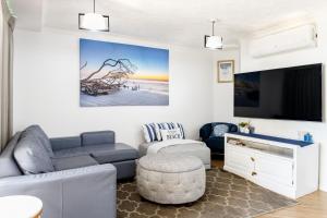 a living room with a couch and a tv at Caloundra Poolside Paradise in Caloundra