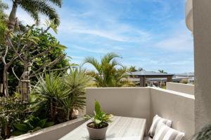 a balcony with a bench and palm trees at Caloundra Poolside Paradise in Caloundra