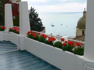 a balcony with red flowers and a view of the ocean at La Tavolozza Residence in Positano