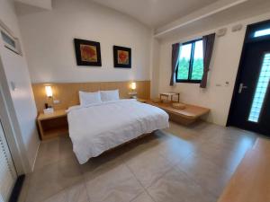 1 dormitorio con 1 cama blanca grande y 2 ventanas en Lakeforest B&B, en Yuanshan