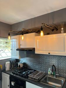 Una cocina con gabinetes blancos y un fregadero. en Studio 14 proche GRR2 97400, en Saint-Denis