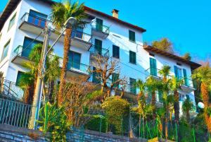 a white building with palm trees in front of it at Belvedere - Apartment with Balcony Lake View in Sala Comacina
