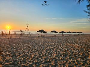 un grupo de sombrillas en una playa con puesta de sol en Celina Peninsula Resort Quảng Bình en Dương Cảnh