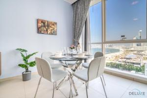 Chic 1BR at Al Bateen JBR by Deluxe Holiday Homes في دبي: غرفة طعام مع طاولة وكراسي ونافذة كبيرة