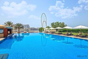 Chic 1BR at Al Bateen JBR by Deluxe Holiday Homes في دبي: حمام سباحة كبير مع عجل فيريس في الخلفية
