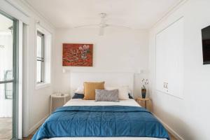 um quarto com uma cama com um edredão azul em Fogo @ Ethel & Ode’s em Bundeena
