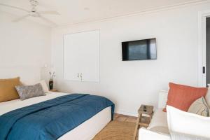um quarto com uma cama e uma televisão na parede em Fogo @ Ethel & Ode’s em Bundeena