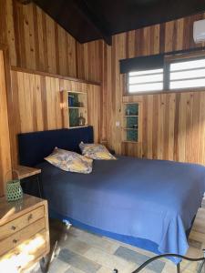 a blue bed in a room with wooden walls at Le Chalet du Domaine in La Saline les Bains