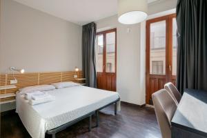 1 dormitorio con 1 cama, escritorio y ventanas en Il Palazz8, en Iglesias