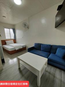 uma sala de estar com um sofá azul e uma mesa em Lu Zhou Hotel em Pingtung