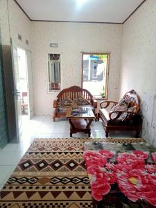 una sala de estar con 2 sillas y flores en el suelo en Mutiara Dieng en Wonosobo
