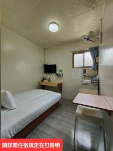 um pequeno quarto com uma cama e uma secretária em Lu Zhou Hotel em Pingtung