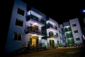 um grande edifício branco com portas verdes e varandas à noite em 3 Bedroom Malaikanzi Apartment em Namulanda
