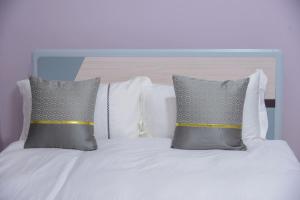 uma cama branca com duas almofadas em cima em 3 Bedroom Malaikanzi Apartment em Namulanda
