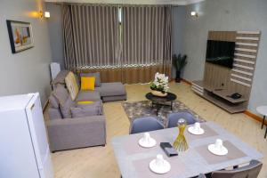 a living room with a table and a couch at 3 Bedroom Malaikanzi Apartment in Namulanda