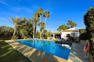 una piscina frente a una casa con palmeras en Villa Cal Roma, en Pollensa