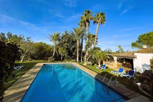 una piscina con dos sillas y una casa en Villa Cal Roma, en Pollensa