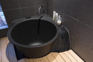 a black bath tub in a bathroom with a shower at Shirafuji-an Modern Private Machiya in Central Kyoto in Kyoto