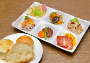 dos platos blancos de comida en una mesa de madera en APA Hotel TKP Sapporo Eki-Kitaguchi Excellent en Sapporo