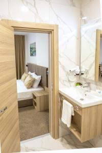 a bathroom with a sink and a mirror and a bed at Evelin Deluxe House in Plovdiv