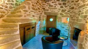 a room with a fireplace and a stone wall at MOULIN DE KERNOT in Cléden-Cap-Sizun