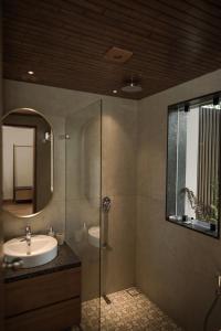 a bathroom with a sink and a shower with a mirror at Tea & Tranquility in Vagamon