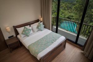 a bedroom with a bed with a view of a balcony at Tea & Tranquility in Vagamon