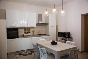 eine Küche mit weißen Schränken sowie einem Tisch und Stühlen in der Unterkunft Doraci Home in Conversano