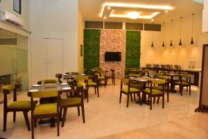 um restaurante com mesas e cadeiras e uma parede verde em Hotel Royal Altis em Vasco da Gama