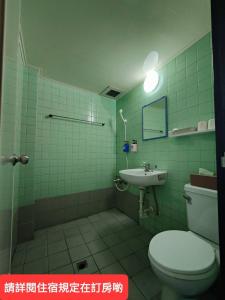 W wyłożonej zielonymi kafelkami łazience znajduje się toaleta i umywalka. w obiekcie Lu Zhou Hotel w mieście Pingdong