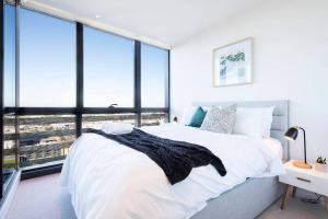a bedroom with a white bed and large windows at Relax and Unwind by the Dock -Car park included- in Melbourne