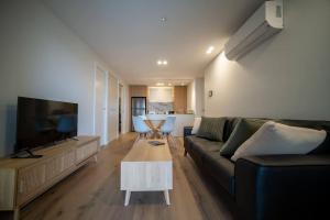 a living room with a couch and a flat screen tv at Stay on Northbourne Ave in Canberra