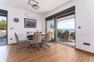 a dining room with a table and chairs and sliding glass doors at Villa Rosemary -semi-detached villa with a pool and a panoramic view, close to a sandy beach - by TRAVELER tourist agency Krk in Risika