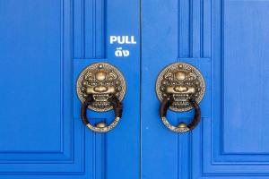 a blue door with a pair of gold door handles at Marco Polo Phuket Poshtel & Bistro in Phuket