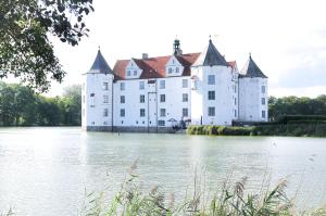 een groot wit kasteel op een waterlichaam bij Ferienwohnung Ankerplatz 54 Nord in Glücksburg