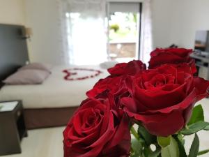 un vaso pieno di rose rosse in una camera da letto di Résid'Spa Loire & Sèvre a Rezé